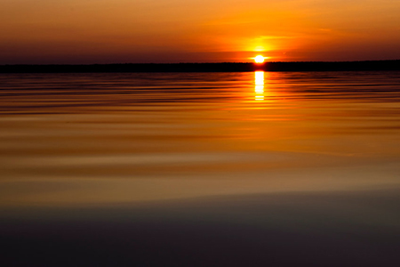 Water surface. View of a Sunset sky background. Dramatic gold sunset sky with evening sky clouds ove