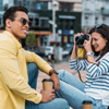 Woman sitting and taking photo of an Asian man