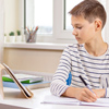 Kid with digital tablet computer writing, doing homework at white desk. Online learning, remote educ