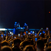 Closeup rear view of large crowd of people enjoying an open air concert on a summer night