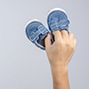 Hand holding old and torn baby shoes as a symbol for precious memory on white background