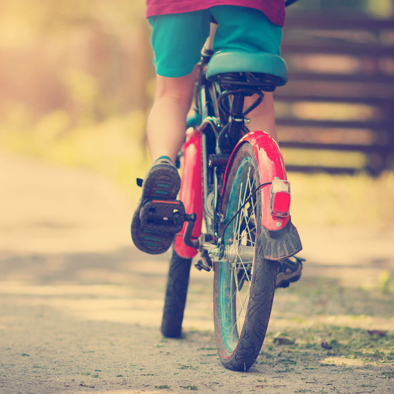 child on a bicycle at asphalt road in early morning