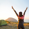 A girl in the mountains, rejoices in the sun. Panoramic view of the mountain and the sea from above.