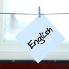 English. Note is written on a white sticker that hangs with a clothespin on a rope on a background o