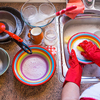 woman washing crockery and cutlery wearing gloves