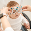 Eye doctor hands putting on ophthalmic trial frame on calm little child