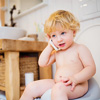 Cute toddler with a smartphone in the bathroom. Little boy sitting on the toilet