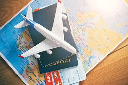 stacked items: map, passport, boarding passes, miniature airplane