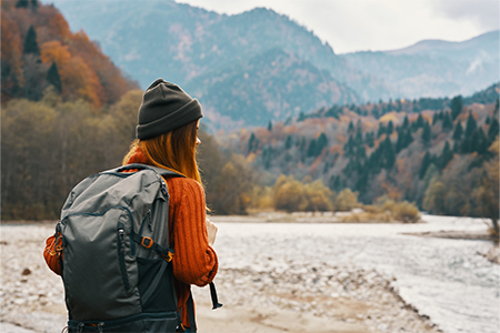 woman with a backpack near the river on nature in the mountains