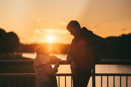 Father and daughter on the bridge at sunset. The concept of a happy family.