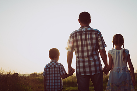 Father and children playing in the park at the sunset time