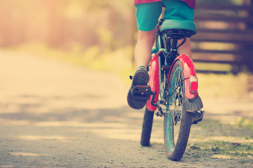 child on a bicycle at asphalt road in early morning