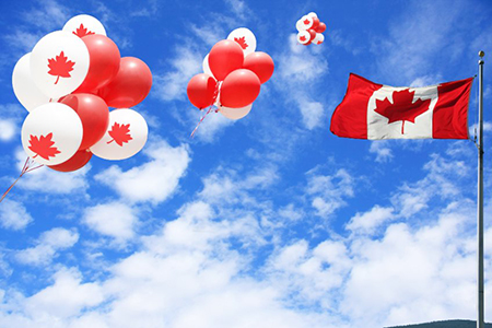 Canadian maple leaf flag and balloons in the sky for canada day.