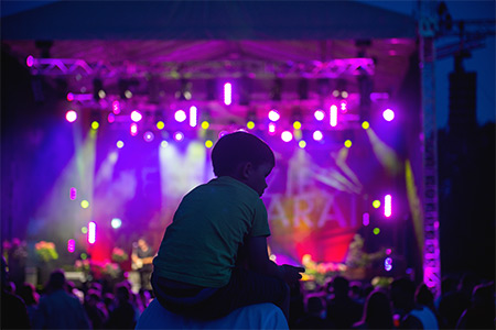 Child sits on the neck of a man laser light background.At the concert