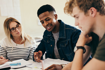 African boy studying with classmates. Group of multi-ethnic students working on college assignments 