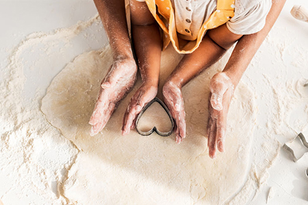 cropped image of african american mother and daughter preparing cookies with heart shaped mold in ki