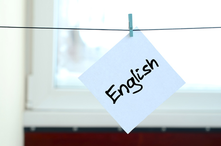 English. Note is written on a white sticker that hangs with a clothespin on a rope on a background o