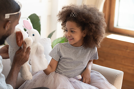  daughter play with father people sit on couch holding soft animals toys acting out fun performance