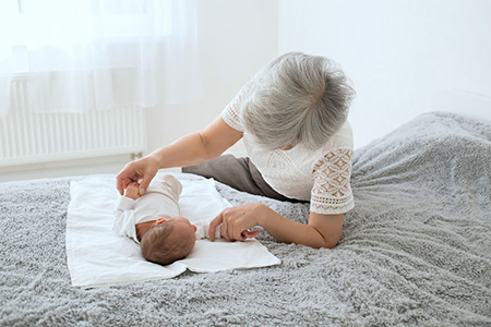 Grandmother admires her sweet granddaughter. Great-grandmother plays with a newborn great-granddaugh