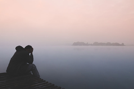 alone man sitting with sadness emotion on wood pier