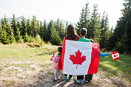 Family of mother with three kids hold large Canadian flag celebration in mountains