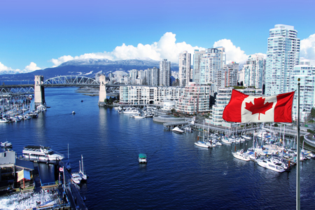 Canadian flag in front of view of false creek and the burrard street bridge in vancouver, canada.