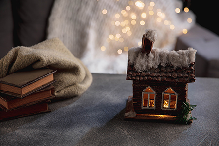 Winter house miniature illuminated and books on grey and white background