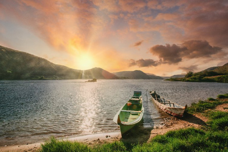 Two canoes at the lakeshore with a beautiful sunrise in the horizon