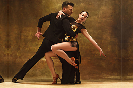 Dance ballroom couple in gold dress dancing on studio background.