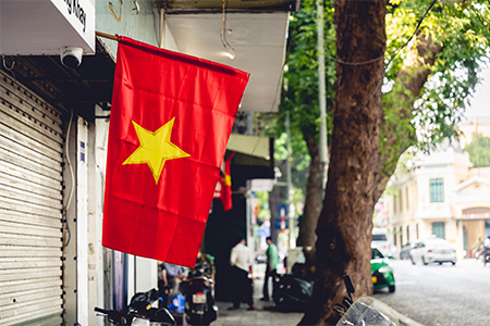 A scenic view of the Vietnamese flag hanging outside of a store