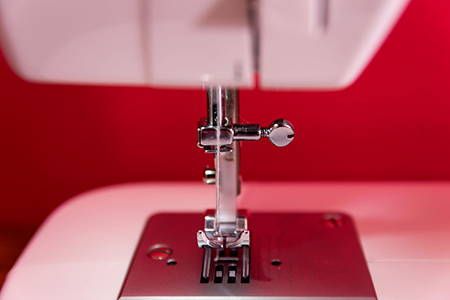 Close up photo of white sewing machine - red background