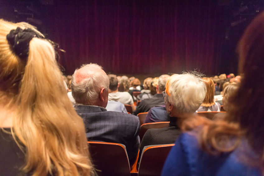 Audience in theathre waiting for drama play to start sen from the rear.