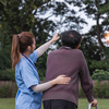 Asian woman caregiver helping senior man walking in nursing home