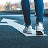 Make decision which way to go. Walking on directional sign on asphalt road. Female legs wearing jean