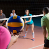 Cropped hand of female player with teammates holding volleyball at court