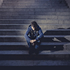 Young desperate man in casual clothes abandoned lost in depression sitting on ground street concrete