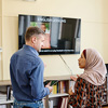 a woman wearing hijab attending English language classes discussing something with her teacher