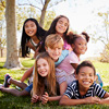 Multi-ethnic group of kids lying on each other in a park