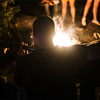 man playing on acoustic guitar and singing song at big bonfire at camp