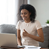 Woman smiling, giving thumbs up to laptop