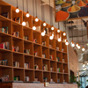 Books Inside Bookshelf Near Lit Pendant Lights in Library