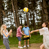 Young women playing volleyball on picnik in spring nature while men preparing grill