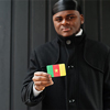 African man wear black durag hold Cameroon flag at hand isolated dark background.