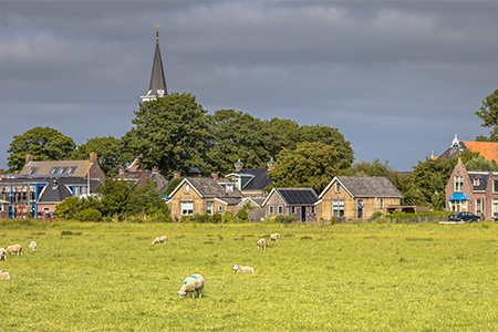 countryside; church houses grassland and sheep under cloudy sky